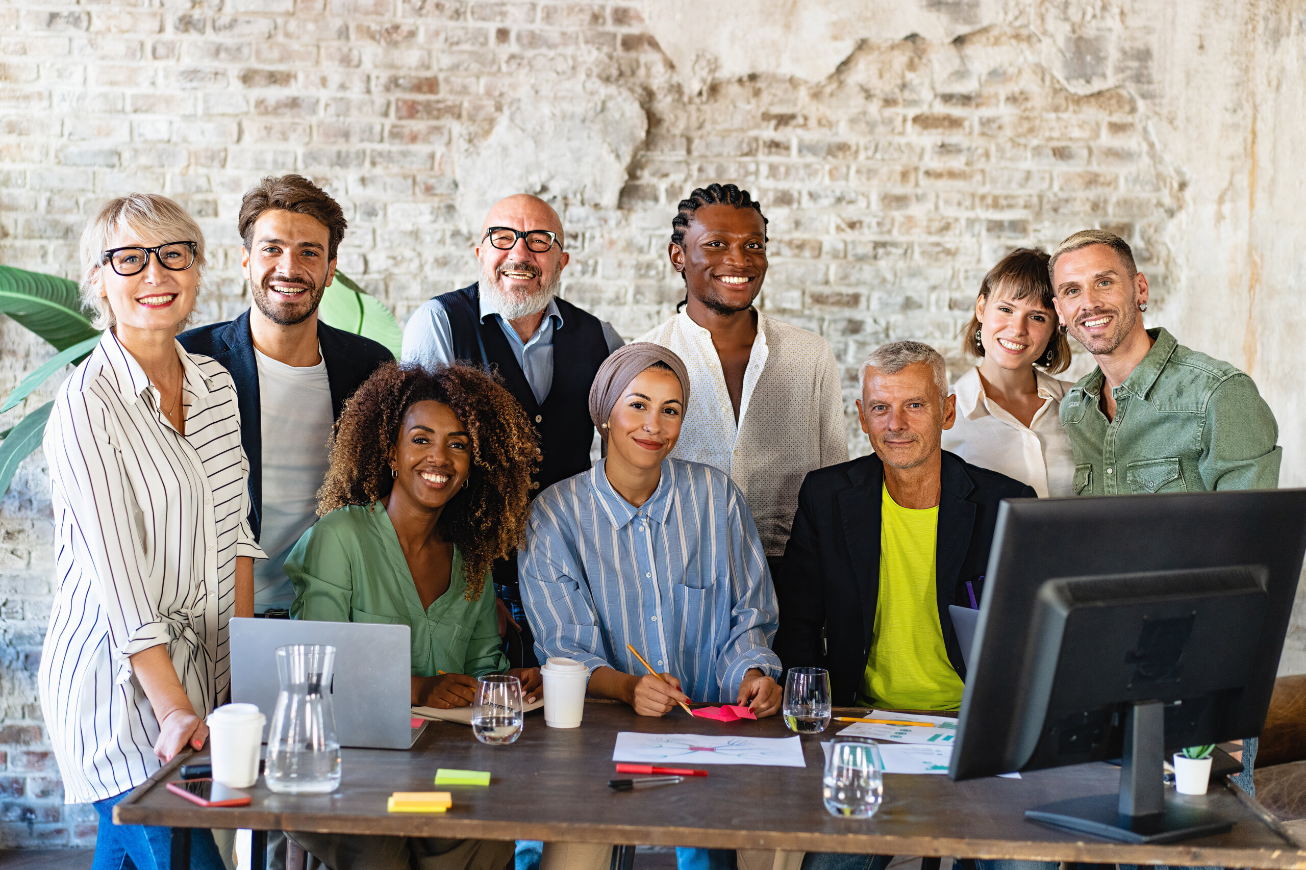 Portrait of successful group of multiethnic business people at modern office looking at camera. Portrait of happy creative team of satisfied businesspeople standing as a team. Multiracial group of people smiling.